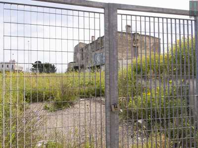 La struttura � circondata da una grande e alta cancellata in metallo chiusa da un grosso lucchetto e sorge solitaria tra l�erba alta e migliaia di gialle margherite